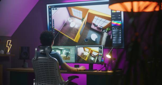 Young 3D designer creates modern house interior, works on design project at home office on computer and big digital screen with professional software interface and tools for 3D modeling and planning.