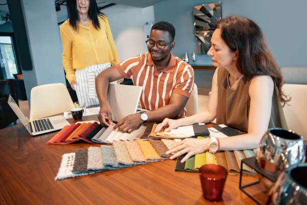 Diverse people working in design studio, using laptop for business developing and consultations. Designer workers using technology for productivity. African man with female Caucasian coworkers. Copy space