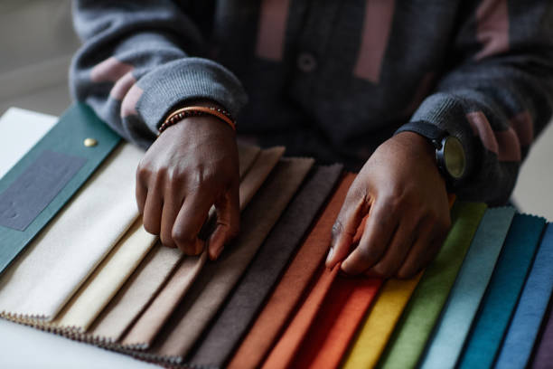 Close-up of African American designer choosing color in colored palette while sitting at table