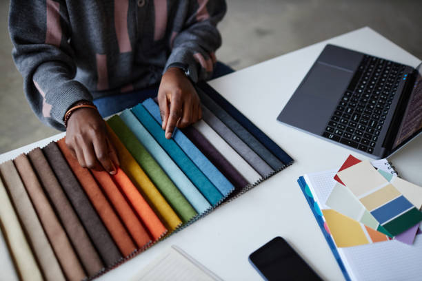 High angle view of designer choosing colour for interior while working at his workplace with laptop and palette