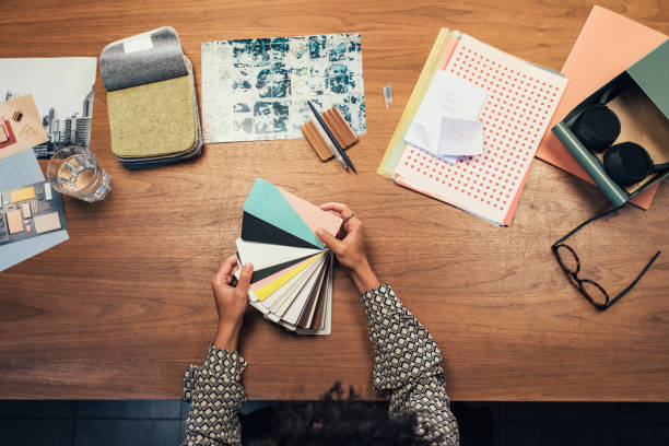 Hands of a designer/architect holding sample papers on her desk.