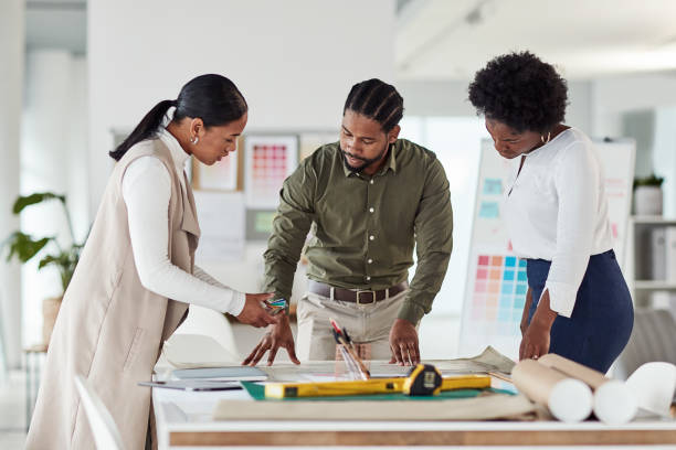 Collaboration, architecture or design with a business team in their office working and planning for building. Architect, engineer and designer with a man and woman employee group at work on strategy